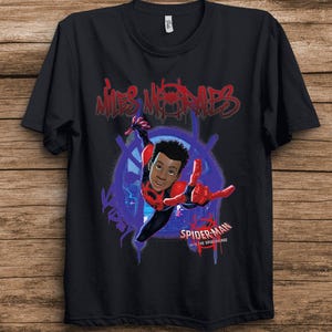 May include: A black short-sleeved t-shirt featuring a graphic of Miles Morales from Spider-Man: Into the Spider-Verse. The design includes red graffiti-style text reading Miles Morales at the top and the movie logo at the bottom right.