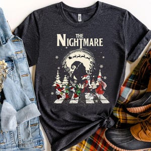 Pode incluir: Camiseta cinza escuro com um gr&aacute;fico de "O Estranho Mundo de Jack". O design mostra personagens atravessando uma rua com um fundo assustador e as palavras "The Nightmare" em branco.