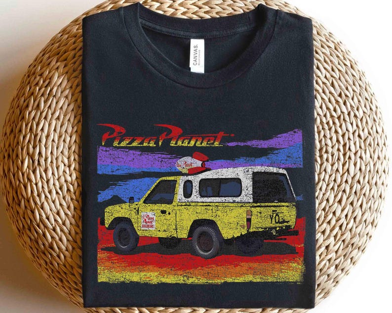 Może przedstawiać: Czarna koszulka z grafiką ciężar&oacute;wki Pizza Planet z Toy Story. Ż&oacute;łta ciężar&oacute;wka ma białą kabinę i czerwono-białe detale. Logo Pizza Planet znajduje się nad ciężar&oacute;wką, z kolorowym tłem zachodu słońca.