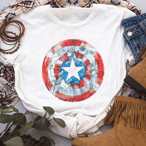 May include: A white ceramic mug with a black handle and the text "But First, Coffee" in a bold, black font. The mug is set against a blurred background, highlighting its clean design.