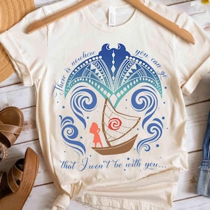 May include: Cream-coloured t-shirt with a boat design, featuring a red and white sail, a figure, and blue ocean waves. The shirt includes the text "There is nowhere you can go that I won't be with you..." in blue script.