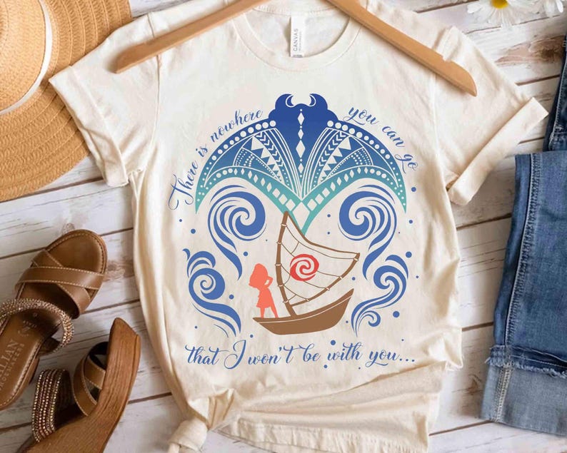 May include: Cream-coloured t-shirt with a boat design, featuring a red and white sail, a figure, and blue ocean waves. The shirt includes the text "There is nowhere you can go that I won't be with you..." in blue script.