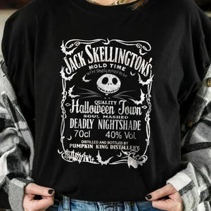 May include: Black crew neck t-shirt featuring a white graphic design. The design includes the text "Jack Skellington's" and "Halloween Town", along with other text and imagery. The shirt also has the text "Deadly Nightshade" and "70cl".