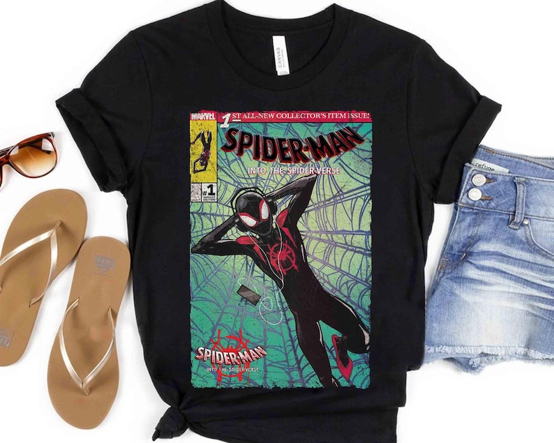 Puede incluir: Camiseta negra con un dise&ntilde;o de portada de c&oacute;mic. El dise&ntilde;o presenta el texto "SPIDER-MAN" y una ilustraci&oacute;n de un superh&eacute;roe. Las palabras "INTO THE SPIDER-VERSE" tambi&eacute;n son visibles.