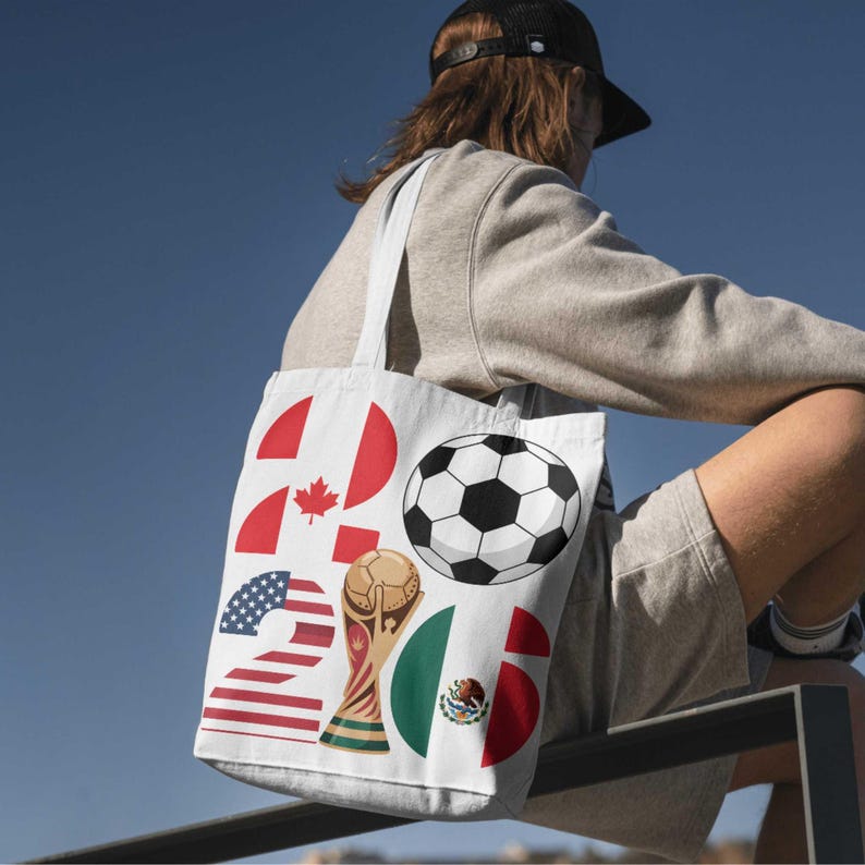 World Soccer Cup 2026 inspired soccer PNG displayed on a white canvas tote bag mockup, featuring the year 2026 with USA, Canada, and Mexico flag designs, a black and white soccer ball, and a gold trophy illustration. This transparent PNG is ideal for print on demand tote bags, fan accessories, soccer gifts, sublimation projects, and football merchandise celebrating the 2026 international soccer tournament.
