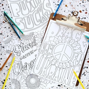 May include: Two black and white colouring pages with a peace sign and sunflowers. The first page says "Stand with Ukraine" and the second page says "Peace Now for Ukraine".