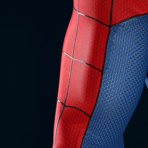 May include: A close-up view of a fabric garment featuring a vibrant red and blue color scheme. The red sections are adorned with a prominent black web pattern, while the blue sections display a subtle, repeating hexagonal texture throughout.