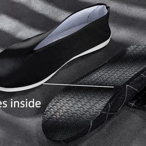 K&ouml;nnte beinhalten: Ein schwarzer Slipper mit wei&szlig;em Innenfutter und wei&szlig;er Zwischensohle. Der Schuh ist von der Seite abgebildet, daneben liegt eine separate schwarze Sohle mit wellenf&ouml;rmigem Profil und gitterartiger Struktur. Der Text "Shoes inside" ist zu sehen.
