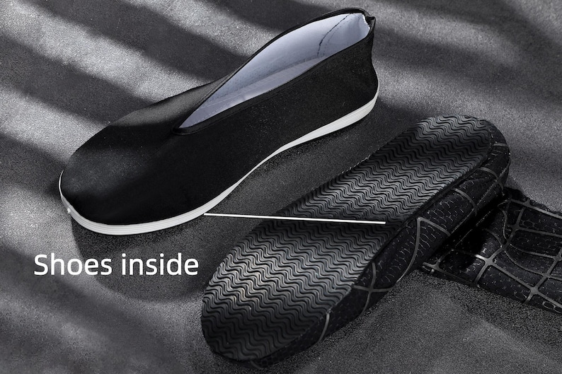 K&ouml;nnte beinhalten: Ein schwarzer Slipper mit wei&szlig;em Innenfutter und wei&szlig;er Zwischensohle. Der Schuh ist von der Seite abgebildet, daneben liegt eine separate schwarze Sohle mit wellenf&ouml;rmigem Profil und gitterartiger Struktur. Der Text "Shoes inside" ist zu sehen.