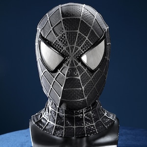 K&ouml;nnte beinhalten: Eine schwarze Vollkopfmaske mit texturiertem Wabenmuster und erhabenen silbernen Netzlinien. Die Maske verf&uuml;gt &uuml;ber zwei gro&szlig;e, kantige, silber umrandete Augenlinsen mit reflektierender Oberfl&auml;che, die den Kopf- und Halsbereich bedecken.