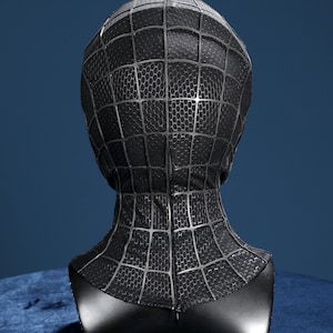 K&ouml;nnte beinhalten: Eine schwarze Vollkopfmaske mit einem erhabenen, dunkelgrauen Spinnennetz-Muster auf der gesamten Oberfl&auml;che. Der Stoff weist eine subtile hexagonale Textur auf und das Design umfasst eine vertikale Naht in der Mitte der R&uuml;ckseite.