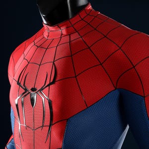 May include: A red and blue long-sleeve shirt featuring a black spider web pattern across the red chest and shoulder panels. A large, black, stylized spider emblem is centered on the chest. The fabric has a textured, honeycomb-like surface.