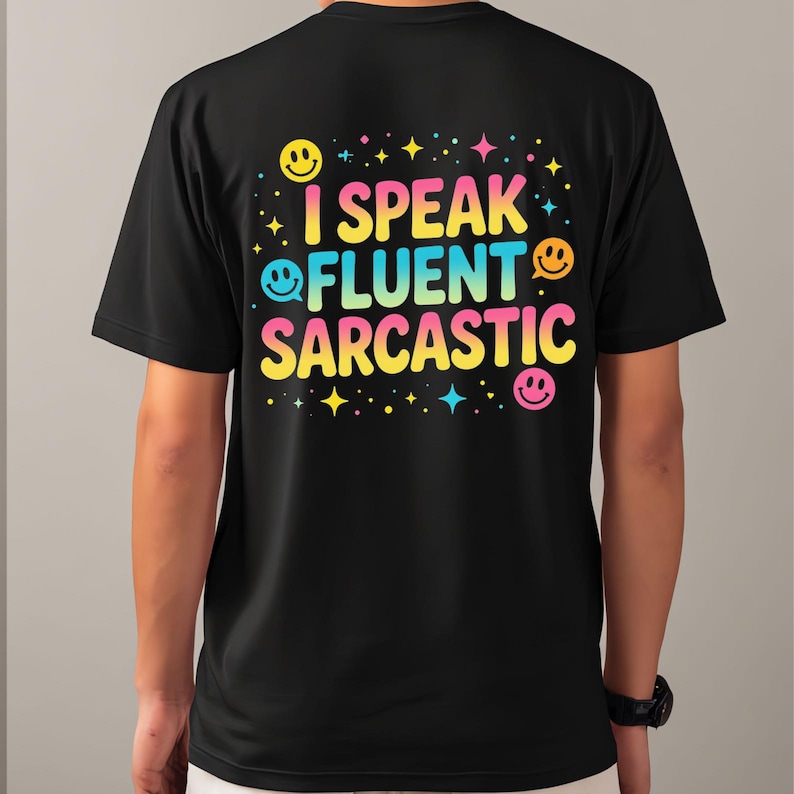 May include: Black t-shirt with the text "I Speak Fluent Sarcastic" in colorful bubble letters. The design includes smiley faces and stars. The shirt is a casual wear item.