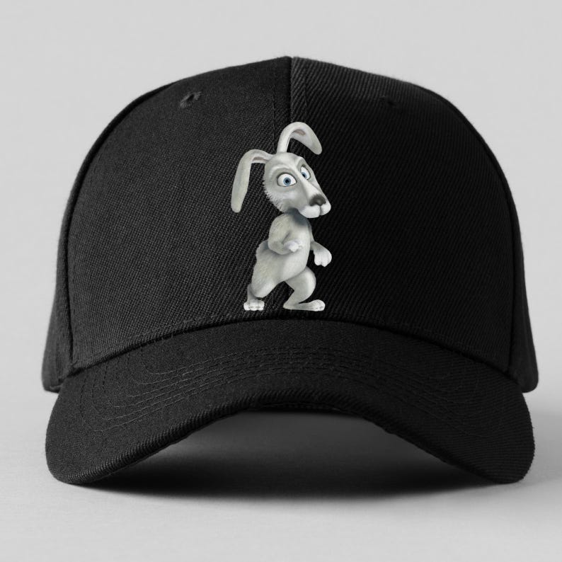 K&ouml;nnte beinhalten: Schwarze Baseballkappe mit einem Cartoon-Kaninchen-Design. Das Kaninchen ist grau mit blauen Augen und langen Ohren. Die Kappe hat einen gebogenen Schirm und einen Knopf oben.