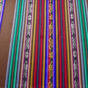 May include: A close-up of a colourful woven fabric with stripes of red, blue, green, yellow, and brown. The fabric has a traditional pattern and is likely made from natural fibres.