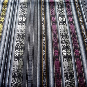 May include: Close-up of a woven fabric with a repeating pattern of geometric shapes and stars in shades of gray, white, yellow, pink, and black.