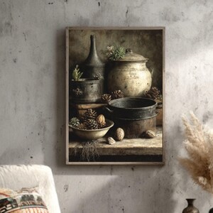 May include: A framed still life painting shows vintage kitchenware, including pots, bowls, and a tall bottle, alongside pine cones and nuts. The artwork hangs above a wooden armchair with a patterned cushion, creating a cosy, vintage-inspired interior scene.