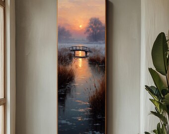 Puede incluir: Pintura enmarcada de un paisaje de atardecer sobre un río con un puente. La obra presenta tonos cálidos de naranja y amarillo en el cielo, reflejándose en el agua. Altas hierbas bordean las orillas, y la pintura está enmarcada en madera.
