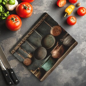 May include: A kitchen-themed still life featuring a cutting board with a vintage copper pot design. Fresh tomatoes, garlic, basil, and a knife are arranged around the board. The color palette includes red, green, and copper tones.