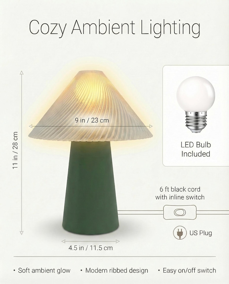 May include: A mushroom-shaped table lamp with a green base and a ribbed, off-white shade. The lamp is 11 inches tall and 9 inches wide. It includes an LED bulb and has a 6 ft black cord with an inline switch. The text "Cozy Ambient Lighting" is at the top.