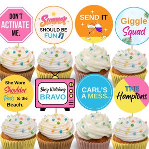 May include: Twelve cupcakes with white frosting and colourful sprinkles. Each cupcake has a decorative topper with phrases like "Don't Activate Me," "Summer Should Be Fun," and "Giggle Squad." The cupcakes are in yellow, pink, and brown cupcake cases.