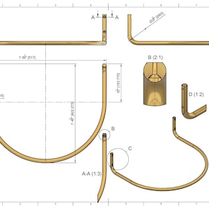 Op de afbeelding: Technische tekening van een goudkleurig metalen object, met verschillende aanzichten en afmetingen. De tekening bevat bovenaanzichten, zijaanzichten en doorsneden, met afmetingen in inches en millimeters. Het object heeft een gebogen ontwerp met een puntig uiteinde, met metingen in cm.