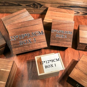 May include: Wooden boxes of various sizes with visible wood grain. The boxes are labeled with dimensions in centimeters, including a 22x19x9.5cm box, a 17x14x9.5cm box, and a 12x12x8cm box. The boxes are labeled as Box 1, Box 2, and Box 3.