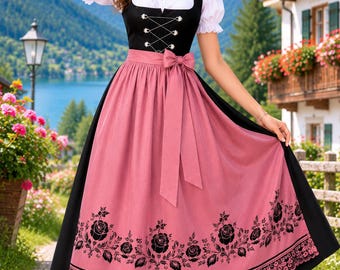 May include: A black dirndl dress featuring a white puff-sleeve blouse, a black bodice with silver lacing, and a long pink apron. The apron is decorated with a black floral rose pattern along the hem and a delicate lace border at the bottom edge.