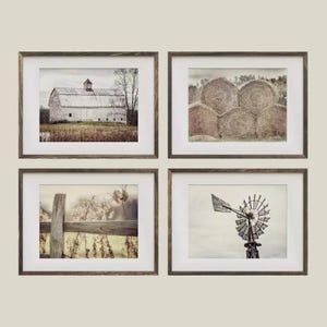 May include: Set of four framed landscape prints. The prints feature a white barn, hay bales, a wooden fence, and a windmill. Each print is in a brown wooden frame with a white matting.
