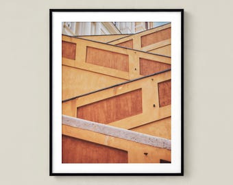 Fotografía sin marco de una escalera en Menton, Francia; arte mural abstracto de arquitectura en tonos dorados y amarillos, Riviera Francesa.