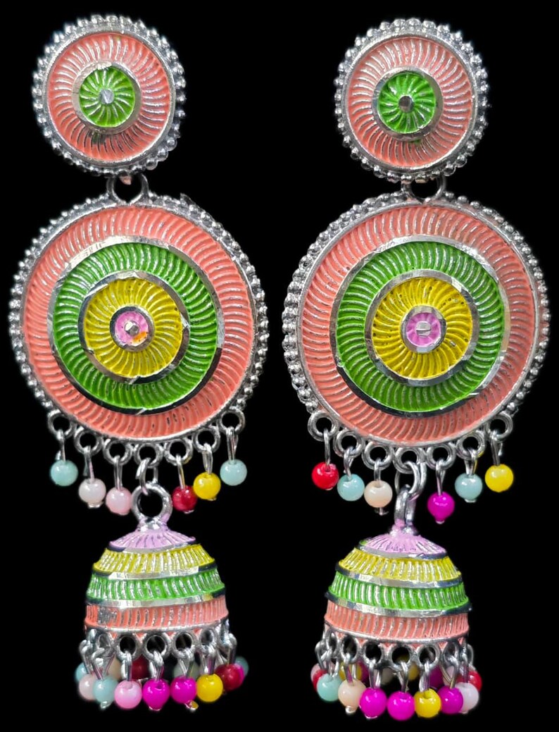 K&ouml;nnte beinhalten: Ein Paar farbenfrohe H&auml;ngeohrringe. Jeder Ohrring hat ein kreisf&ouml;rmiges Design mit konzentrischen Ringen in Rosa, Gr&uuml;n und Gelb. Kleine, bunte Perlen h&auml;ngen von unten, und die Ohrringe haben eine silberfarbene Metalloberfl&auml;che.