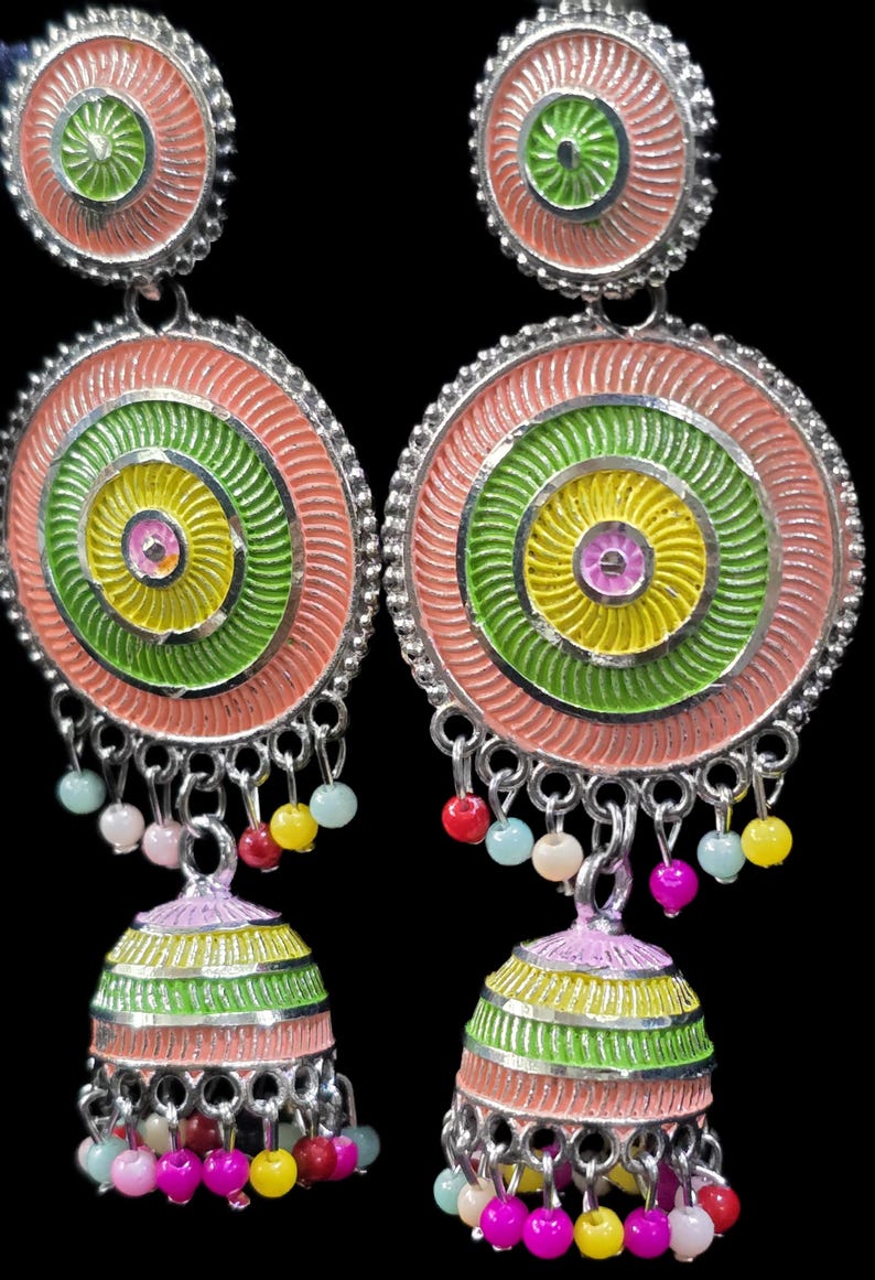 K&ouml;nnte beinhalten: Ein Paar bunte H&auml;ngeohrringe. Jeder Ohrring hat ein kreisf&ouml;rmiges Design mit konzentrischen Ringen in Rosa, Gr&uuml;n und Gelb. Kleine, farbige Perlen h&auml;ngen von unten, und die Ohrringe haben eine silberfarbene Metalloberfl&auml;che.