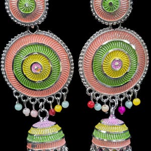 K&ouml;nnte beinhalten: Ein Paar bunte H&auml;ngeohrringe mit kreisf&ouml;rmigem Design. Die Ohrringe haben konzentrische Kreise in Rosa, Gr&uuml;n und Gelb mit einem kleinen glockenf&ouml;rmigen Anh&auml;nger am unteren Ende. Kleine, farbige Perlen h&auml;ngen von der Unterseite der Ohrringe.