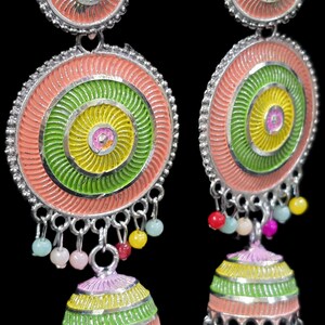 K&ouml;nnte beinhalten: Bunte H&auml;ngeohrringe mit kreisf&ouml;rmigem Design. Die Ohrringe haben konzentrische Kreise in Rosa, Gr&uuml;n und Gelb mit kleinen Perlenakzenten. Die Ohrringe haben eine silberfarbene Metalloberfl&auml;che und einen glockenf&ouml;rmigen Boden.
