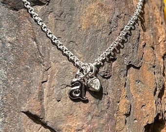 Collar con inicial de plata de ley y un pequeño dije de corazón de circonita cúbica.