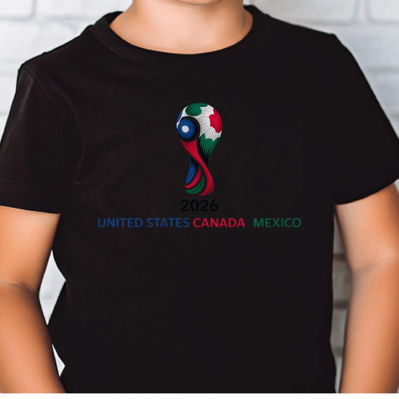 May include: Black t-shirt featuring a colorful graphic of a soccer ball with the text "2026 UNITED STATES CANADA MEXICO" in blue, red, and green. The design is centered on the front of the shirt.