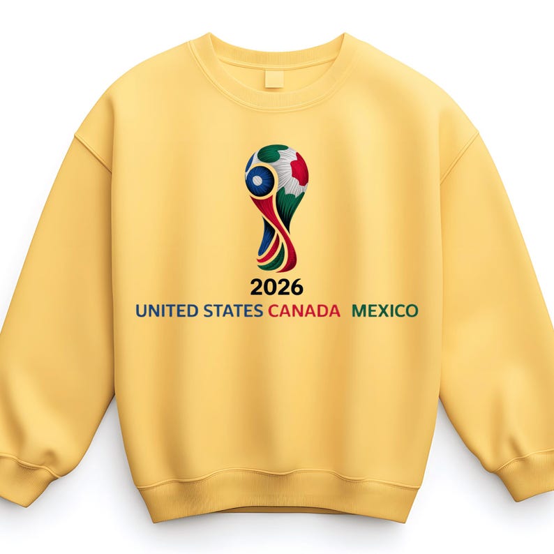 May include: A yellow sweatshirt featuring a graphic of a soccer ball trophy with the text "2026 UNITED STATES CANADA MEXICO". The design is in the center of the sweatshirt.