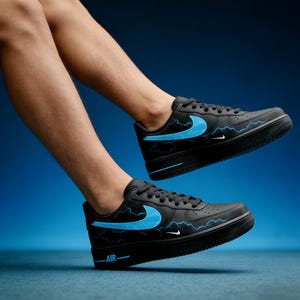 May include: Black sneakers with a blue lightning bolt design and a blue swoosh logo. The shoes have a black sole and the word "AIR" is printed in white. The background is a gradient of blue.