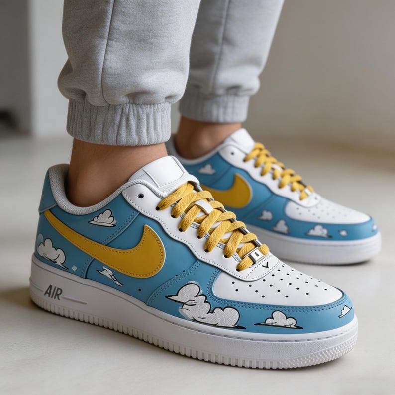May include: Customised blue and white trainers with yellow detailing. The shoes have a cartoon cloud design, yellow swoosh, and yellow laces. The word "AIR" is visible on the side of the white sole.
