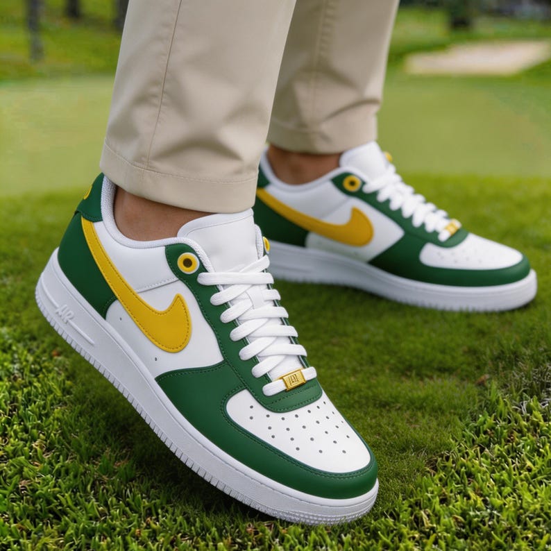 May include: White, green, and yellow sneakers with white laces. The sneakers have a green toe and heel, a yellow swoosh, and a white sole. The shoes are on a green grassy surface.