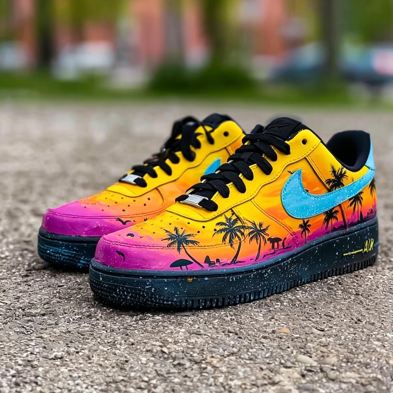 May include: A pair of custom Air Force 1 sneakers. The shoes feature a vibrant sunset design with yellow, orange, and pink hues. Black palm tree silhouettes and a light blue swoosh logo add to the tropical theme. The soles are black with a speckled pattern.