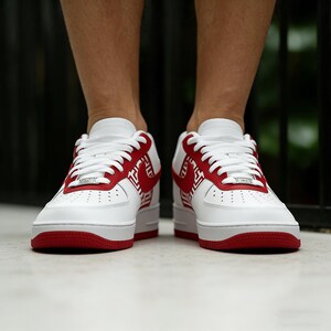 Puede incluir: Zapatillas deportivas blancas y rojas de corte bajo. Las zapatillas presentan una base blanca con detalles rojos en la suela, el tal&oacute;n y el logotipo lateral. Cordones blancos y una etiqueta met&aacute;lica plateada.