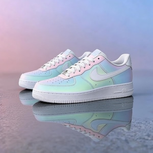 May include: A pair of iridescent sneakers with a pearlescent finish. The shoes have a white sole, laces, and Nike swoosh. The color gradient transitions from light blue to pink and green. The shoes are reflected in the shiny surface.