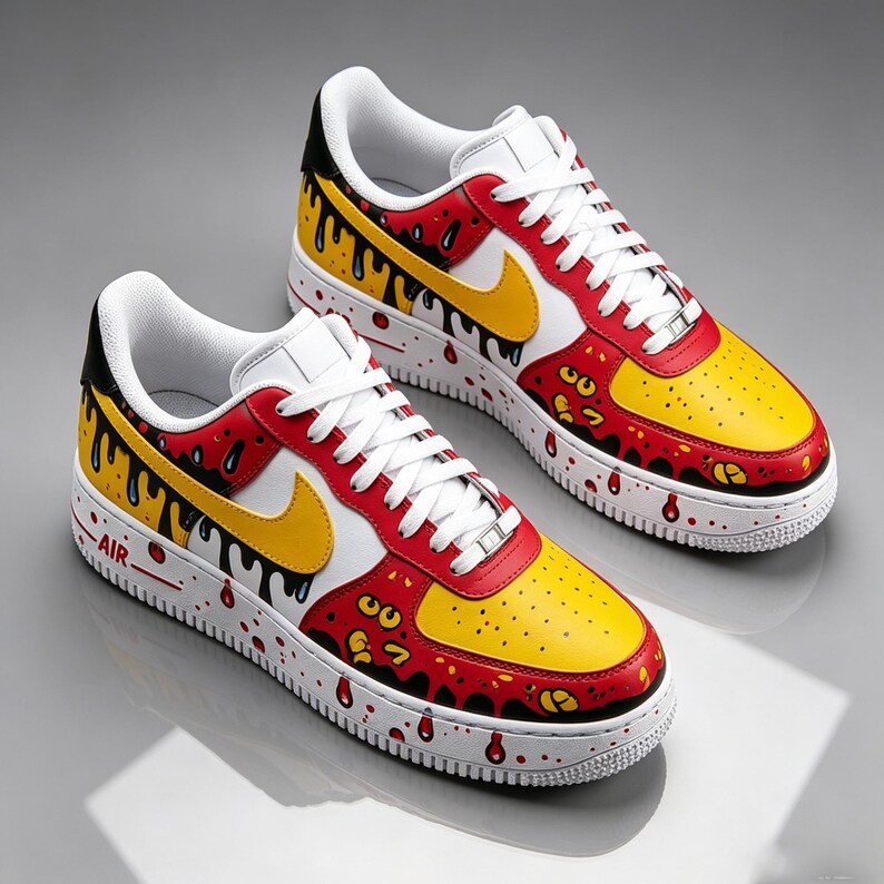 Puede incluir: Un par de zapatillas pintadas a medida. Las zapatillas presentan una puntera amarilla, detalles rojos y un logotipo blanco. Gotas negras y salpicaduras rojas adornan la entresuela blanca. Cordones y leng&uuml;eta blancos.