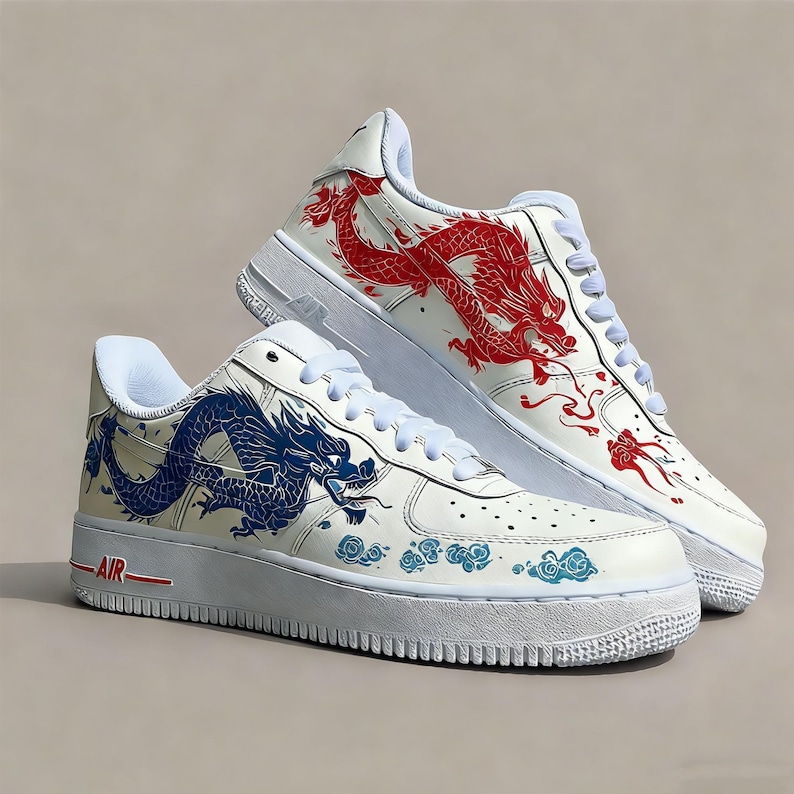 May include: Pair of white sneakers with dragon artwork. One shoe features a red dragon design, the other a blue dragon. Both shoes have white soles and laces, with the word "AIR" in red.