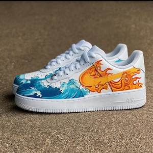 May include: White sneakers with custom artwork featuring ocean waves and flames. The design includes a blue wave pattern on the toe and a fiery orange and yellow design on the side, with a white sole and laces.