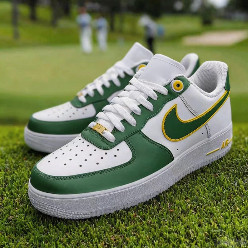 May include: White and green sneakers with a yellow swoosh logo. The shoes have white laces and a white sole. The sneakers are on a green grassy surface.