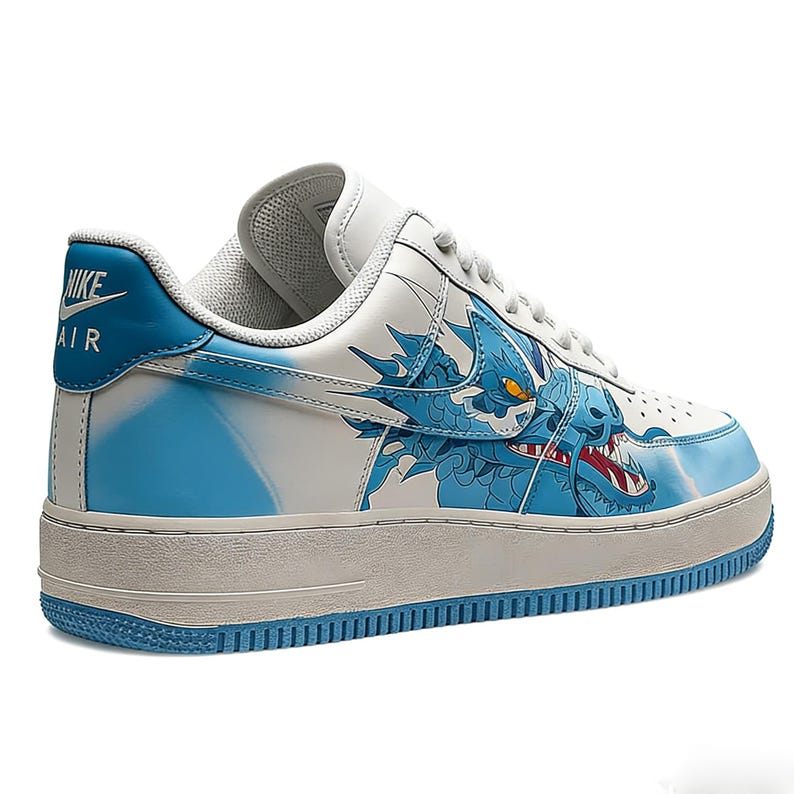May include: White and blue Nike Air Force 1 sneakers with a dragon design. The sneakers feature a white base with blue accents and a detailed dragon illustration on the side. The Nike Air logo is visible on the heel.