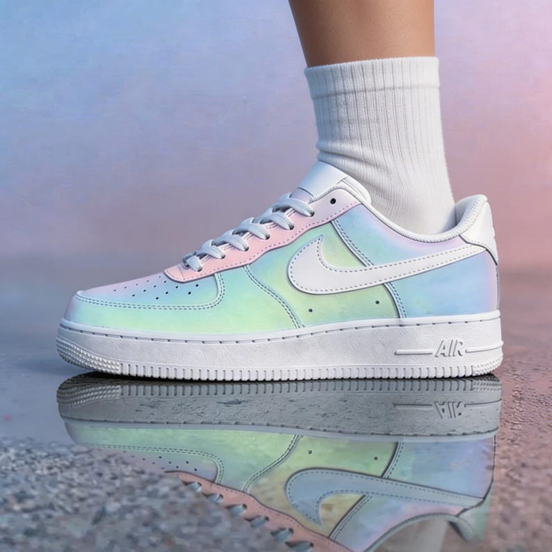 May include: A white and iridescent Air Force 1 sneaker with a pastel color scheme. The shoe features a white sole, a pink and blue upper, and a white Nike swoosh. The word "AIR" is visible on the side of the sole.