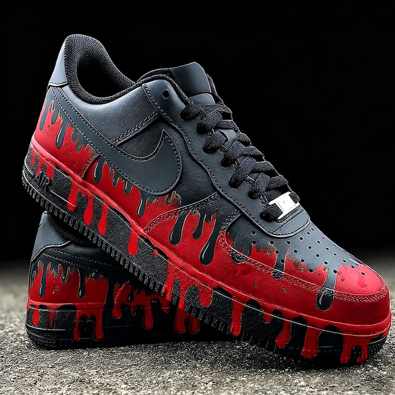 May include: Black and red Air Force 1 sneakers. The shoes feature a black base with a red dripping paint design on the midsole and toe. The Nike swoosh is black, and the laces are black.